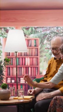 Dikey Video Yaşlısı çift coşkulu vitamin haplarını bir bardak suya koyup ilaçlarını evde hazırlıyorlar. Mutlu insanlar emeklilik ve günlük ilaçlar konusunda iyimser ve iyi hissediyorlar.