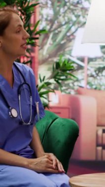 Dikey video hemşire uzmanı, yaşlı bir çiftin iyileşmelerine destek verdiğini gösteren bir bakım hizmeti sunuyor. Rahatlatıcı ve profesyonel bir sosyal ziyaret için kıdemli yaşam desteği ve sağlık yardımı