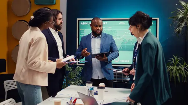 stock image Supervisor and employees attend a status update meeting with their progress portfolios on the current business project. Team leader reviewing marketing strategies and budget planning. Camera B.