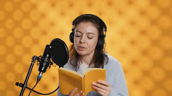 stock image Narrator wearing headphones, reading aloud from book into microphone, exhaling after finally finishing job. Person recording audiobook, creating engaging media content for listeners, camera A