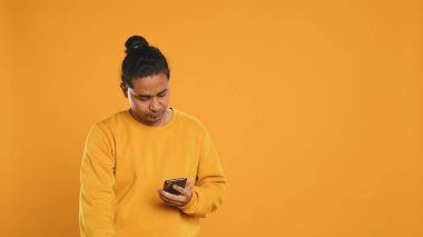 Termal sırt çantalı bir adam telefona cevap veriyor, müşterilerin siparişlerini yerine getiriyor, stüdyo arkaplanı. Yemek servisi çalışanı müşterilere teslimat yapıyor, akıllı telefondan konuşuyor, kamera A