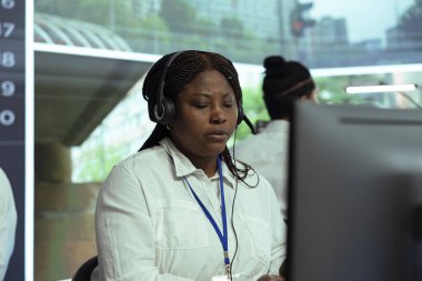 Afrikalı Amerikalı bir kadın gerçek zamanlı güvenlik kamerası görüntülerine bakıyor ve plaka tanıma radar sistemine dayanarak yasa dışı araç kullanma ihbarı yapıyor. CCTV güvenlik kameralarında çalışan bir çalışan..