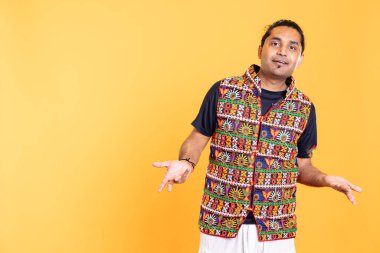 Neşeli bir adamın portresi sallanıyor, cevaplar arasında sallanıyor, omuz silkiyor. Göz alıcı kişi el hareketlerini sorguluyor, karşılık vermekte tereddüt ediyor, stüdyo arka planında izole edilmiş.