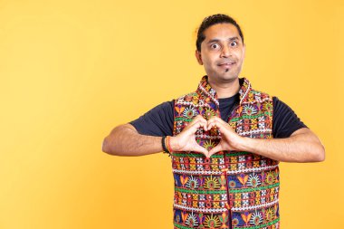 Kalp sembolü hareketi yapan neşeli, dost canlısı bir adamın portresi. Sevgi dolu jestler yapan, minnettar olan, stüdyo arka planında izole edilmiş neşeli bir insan.