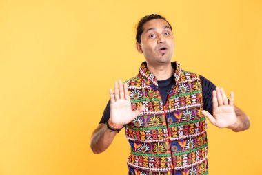 Portrait of assertive man trying to stop misunderstanding using calming hand gesture to diffuse tensions, doing peaceful resolution. Indian person doing calm down sign gesturing, isolated over studio clipart