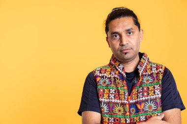 Portrait of man wearing colorful vest standing, looking at camera, isolated over studio background. Close up shot of person dressed in traditional attire, studio backdrop, camera A clipart