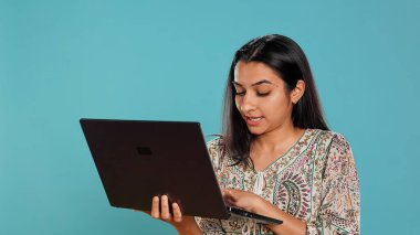 E-posta yazan, dizüstü bilgisayarda dikkatlice yazan, ne yazacağını düşünmekte zorlanan bir kadın. Hintli kişi internetten e-posta gönderiyor, beyin fırtınası mesajı fikri, stüdyo arka planı, kamera B