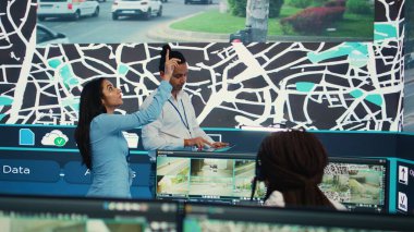 Uydu haritasındaki trafik güzergahlarını inceleyen Hintli yöneticiler, ekspres teslimatı sağlamak için güvenlik kameralarının verilerini topluyorlar. GPS ağlı kamyonların izini süren ve yerlerini belirleyen çalışanlar. Kamera B.