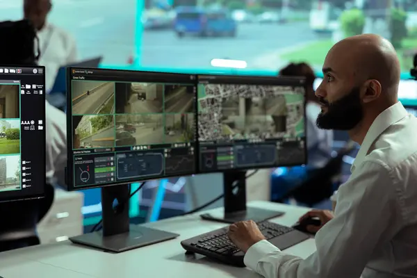 stock image Middle eastern employee monitoring traffic surveillance footage on displays, using radar and CCTV system in observation room. Expert handling license plate recognition on security cameras.