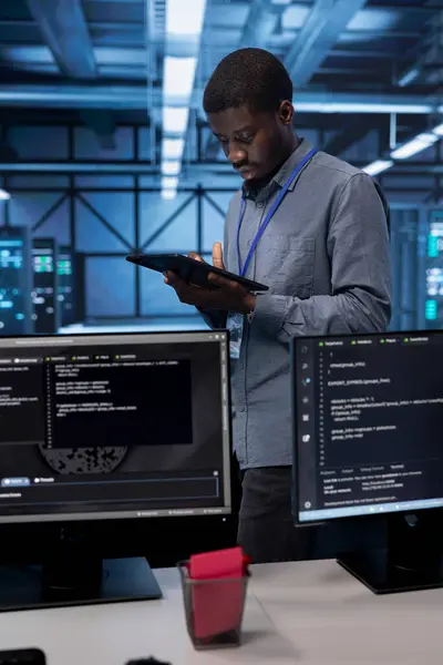 stock image Admin in data center using diagnostic tools and system monitoring software on tablet device to identify root cause of errors. IT professional in server farm repairing infrastructure