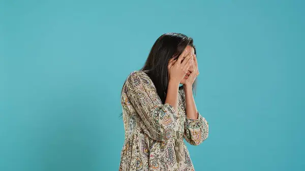 stock image Fearful indian woman covering face with palms, worried about troubling peril, isolated over studio background. Insecure person fearing endangerment, feeling distressed in face of adversity, camera A