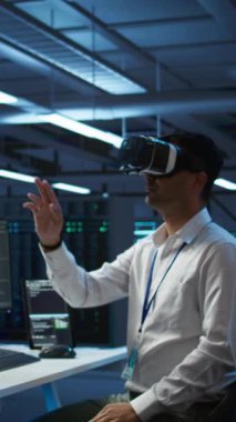 Veritabanında VR kulaklık takan dikey video mühendisi bilgisayara yazılım yüklüyor, sorun yaratıyor. Sanal gerçeklik teknolojisi kullanarak sunucu merkezinde bilişim uzmanı, performans oluşturuluyor