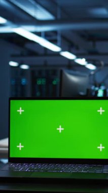 Dikey video, yüksek teknoloji veri merkezindeki mühendislerin güvenlik tehditlerini izlemek için kullandıkları izole ekran laptopuna odaklan. İşçilerin uyum sağlaması için kullandıkları krom anahtar defterini kapat