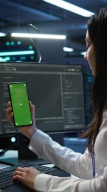 Yeşil ekran cep telefonu kullanarak veri merkezini denetleyen dikey video işçisi, sistemin ağ görevlerini yerine getirmesini sağlıyor. Boş kopyalama alanı ile ağ trafiğini izleyen sunucu odası uzmanı