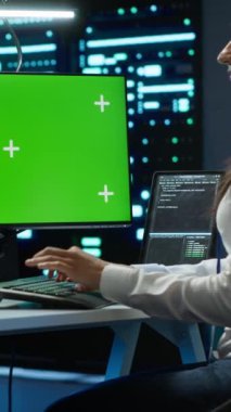 Dikey video teknisyeni yapay zekanın veri işleme gereksinimlerini optimize etmek için yeşil ekran sunucu merkezini kontrol ediyor. İşçi, model bilgisayar kullanarak makine öğrenimi için kullanılan veri merkezini denetliyor