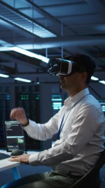 Yüksek teknoloji VR kulaklık takan ağ sistemlerinin kurulumundan sorumlu dikey video veri merkezi yöneticisi. BT çalışanı sanal gerçeklik teknolojisi kullanarak sunucu çiftliği teçhizatını tamir ediyor.