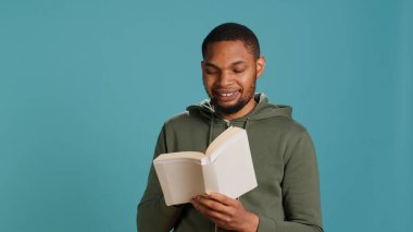 Komik kitap okurken gülen bir adam, ilgi çekici bir hikayeyle eğleniyor. Eğlenen, edebiyat romanı ile eğlenen neşeli insan stüdyo arka planında boş zamanlarında, kamera A