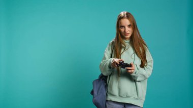 Euphoric woman playing intense gaming console game, celebrating win, studio background. Ecstatic young girl using controller, excited after being victorious in videogame, camera B clipart