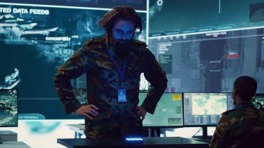 Piyade birliği lideri, askerlerin görev detaylarını oluşturmak için yüksek teknolojili hologramlarla çalışan bir holografik görüntü üzerine uydu görüntülerini inceliyor. Denizde düşman gemilere saldırmanın yolları. Kamera A.