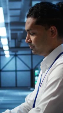 Gülümseyen veri merkezi teknisyeninin dikey video portresi ağ çözme ekipmanlarının kurulumu ve onarımından sorumludur. Sunucu odası altyapısında bakım yapan neşeli bilişim uzmanı