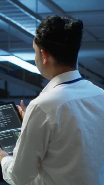 Dikey video veri merkezi bilgisayar bilimcisi ağ donanımı çözme görevlerinin kurulumundan sorumlu. İşteki Hintli adam sunucu odası altyapısında bakım yapıyor, kamera A.