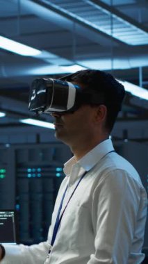 Veritabanında VR kulaklık takan dikey video mühendisi bilgisayara yazılım yüklüyor, sorun yaratıyor. Sanal gerçeklik teknolojisi kullanarak sunucu merkezinde bilişim uzmanı, performans oluşturuluyor