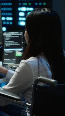Belden aşağısı felçli olan dikey video kişi veri merkezini denetliyor ve iyileştirmeler yapıyor. Tekerlekli sandalyedeki kadın veri merkezinde görev yapıyor, ağ trafiğini takip ediyor, kamera A
