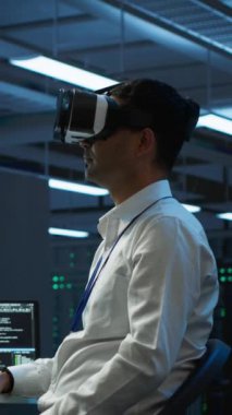 Veri merkezindeki dikey video programcısı, veri bütünlüğü ve güvenliğini sağlayarak, gelecekçi VR kulaklığı kullanarak veri tabanlarını yönetiyor ve koruyor. Sanal gerçeklik kullanarak sunucu oda sistemlerini güncelleme uzmanı