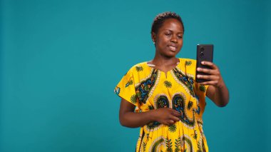 Çevrimiçi bir video çağrısına cevap veren, web kamerasına gülümseyen ve arkadaşlarıyla tartışan kendinden emin mutlu bir insan. Mavi arkaplana karşı uzak video konferans ağı. Kamera B.