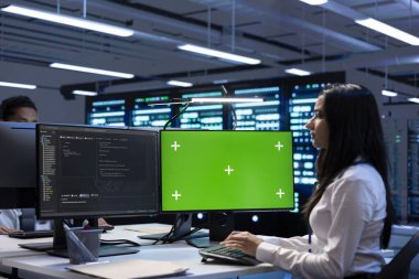 Veri merkezindeki iş arkadaşları altyapıyı yeniledikten sonra yeşil ekran bilgisayarındaki ekipman performansını kontrol ediyorlar. Mühendisler sunucu odasındaki süper bilgisayarlarda bakım yapıyorlar. Model bilgisayar kullanarak.