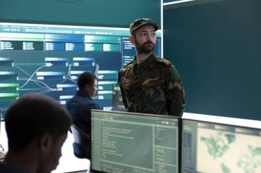 İleri teknoloji ve büyük ekran kullanarak gözetleme ve casusluk faaliyetleri yürüten askeri bilişim uzmanları. Siber tehditlere ve dijital paralı askerlere karşı korunan devlet dairesi.