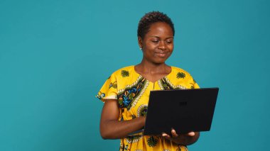 İnternetteki sosyal medya sayfalarını kontrol etmek için internet ağına bağlanan düşünceli bir kadın, stüdyoda bir dizüstü bilgisayarda web sitelerine göz atıyor. Serbest çalışmak için elinde kablosuz bilgisayar tutan genç bir yetişkin. Kamera A.