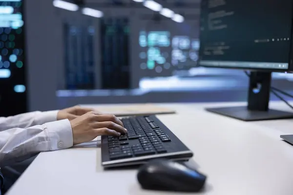 stock image Close up shot of engineer in data center typing on keyboard, working on computer to do checkup on hardware mainframes. IT professional inputting data on PC in server farm