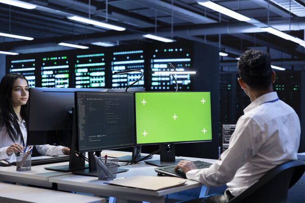 Admin coworkers using mockup computer monitor to check server clusters configuration settings. Professionals checking event logs in monitoring software on chroma key PC in data center