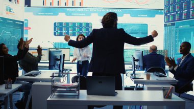 Ekibiyle birlikte genişleme sürecini kutlayan işletme yöneticisi, organizasyonun çalışma sahasında zıplıyor. CEO, yeni verimli yatırım ve işbirliğinden memnun. Kamera B.