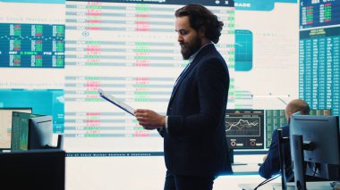 İcra subayı ofisteki büyük ekranda gösterilen verileri inceler, bilgi ekranları, finans analizleri ve organizasyonel gelişmeleri inceler. Telekomünikasyon sistem kontrol odası. Kamera A.