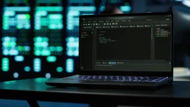 Veri merkezindeki laptop ekranında çalışan kodların kapatılması vites enerji tüketimini yönetmek için kullanılır. Sunucu çiftliğindeki bulanık arkaplanda yazılım geliştirici tarafından kullanılan deftere odaklan, kamera A