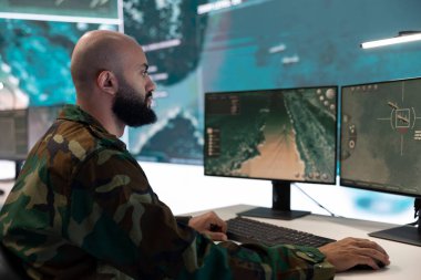 Piyade birimi subayı, komuta merkezinde yüksek teknoloji anti-terörizm gözetleme sistemi çalıştırarak, askeri kontrol odasındaki bilgisayarla ilgili büyük verileri inceliyor. Erkek ordu subayı ulusal güvenliği sağlar..