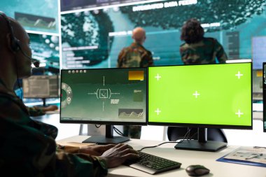 Askerler, askeri üsteki bir bilgisayardaki savaş alanı uydu verilerini izleyerek, güvenlik kamerası ve yeşil ekran görüntülerini inceliyor. Asker bilişim mühendisi keşif sistemi kullanıyor.