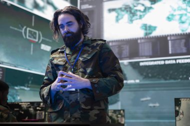 Ordu askeri, kontrol merkezindeki bir hologram projeksiyonunun bilgilerini inceliyor. Piyade birliği için bir savaş alanı haritası oluşturuyor. Görevli gözetim sistemini izliyor..