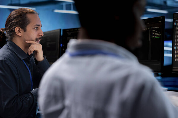 IT engineers in data center facility using diagnostic tools and system monitoring software to identify root cause of malfunctions. Colleagues in server hub repairing equipment together
