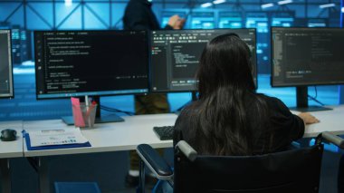 Sunucu çiftliğinde arızalı bir kadın pano dosyalarında donanım parametrelerine bakıyor. Veri merkezinde tekerlekli sandalye kullanıcısı evrak okuyor, platformların performansını gözden geçiriyor