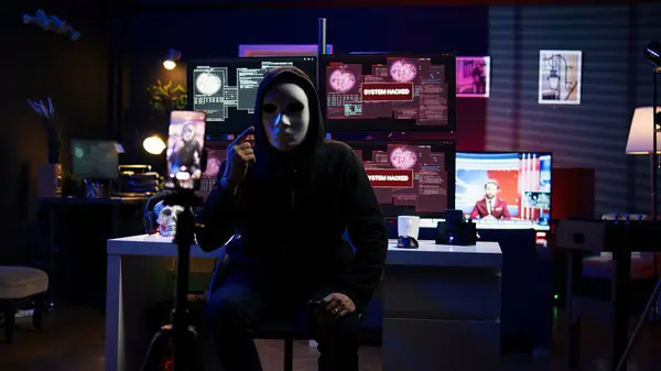 stock image Hacker concealing identity filming ransom video in hidden underground base, threatening to release stolen data publicly if payout demands are not met, using phone to record blackmail footage, camera B