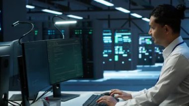 Veri merkezinde sunucuları, işletim sistemlerini ve yazılım programlarını yöneten iyimser yöneticinin portresi. Sunucu merkezinin güvenli ve düzgün çalıştığından emin olmak için neşeli bir uzman, Kamera A