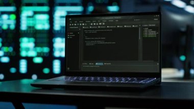 Modern veri merkezinde kodlama yapan mühendislerin kullandığı dizüstü bilgisayara odaklanın, güvenlik tehditlerini izleyin. A kamerasının yönetmeliğe uymasını sağlamak için çalışanların bulanık arka planda kullandığı defteri kapat.
