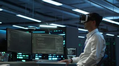 Veri merkezindeki programcı, gelecekteki VR kulaklığı kullanarak veri tabanlarını yönetir ve korur, veri bütünlüğü ve güvenliğini sağlar. Sanal gerçeklik kullanarak sunucu oda sistemlerini güncelleme uzmanı