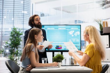 Ekranda müşterilere ipo trendlerini ve ekonomik göstergeleri gösteren mali danışman. Komisyoncu, yatırım fırsatlarını belirlemek için ebeveyn ve genç stratejileri sunmak için büyük ekranı kullanıyor