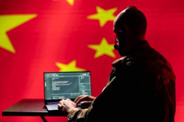 Chinese programmer making bot accounts spreading fake news online meant to criticize Western countries. Computer scientist working for China programming troll farm promoting communist ideology clipart