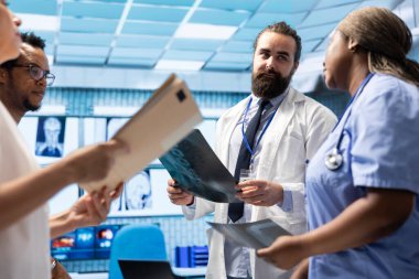 Tıp uzmanları çalışanlarla yaptıkları toplantıda radyografi taramalarını analiz ederek yeni tedavi seçenekleri geliştirmeye çalışıyorlar. Analiz ve tanı kontrolü için takım çalışması yapmak, sağlık çözümleri.