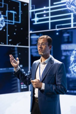 Teknoloji fuarında konuşan adam en son yapay zeka teknolojisi trendlerini ve vaka çalışmalarını araştırıyor. Bilgisayar bilimcisi büyük olay sırasında en son yapay zeka yeniliklerini sunuyor.